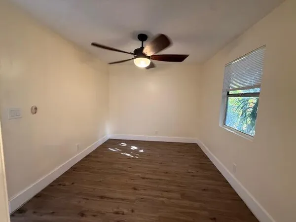 a view of a room with wooden floor and a ceiling fan