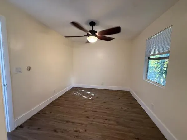 an empty room with wooden floor fan and windows