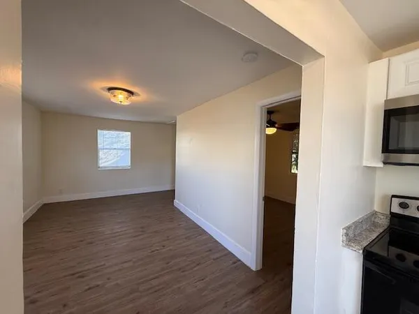 a view of an empty room with a window and wooden floor