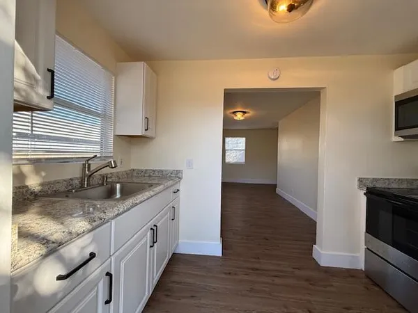 a kitchen with granite countertop a sink and a stove top oven