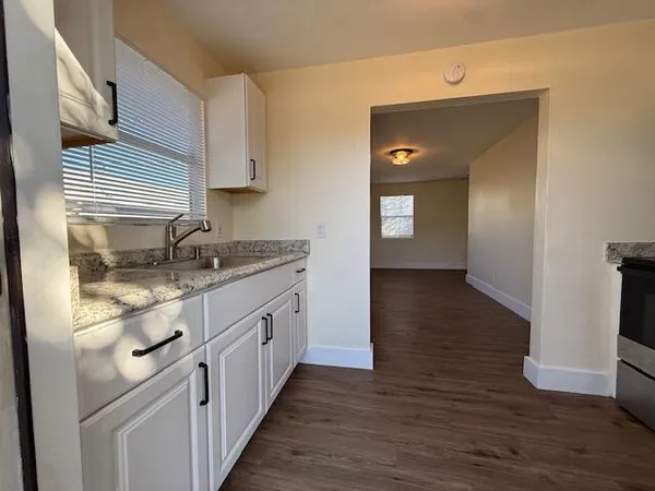 a kitchen with granite countertop white cabinets and wooden floor