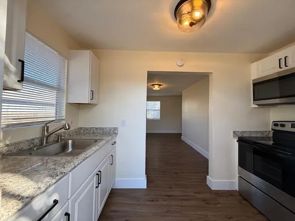 a kitchen with granite countertop a sink and a stove top oven