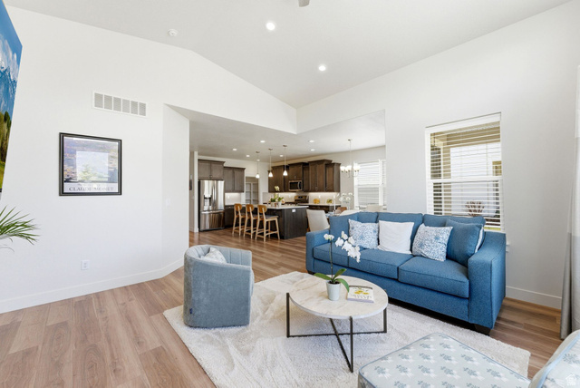 108 West Monte Rosa Lane Midway, UT 84049 - Photo 12 of 48 Open-concept living area featuring vaulted ceilings, wood-finish flooring, a kitchen with dark cabinetry, and stainless steel appliances