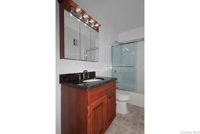 a bathroom with a granite countertop sink a toilet and mirror