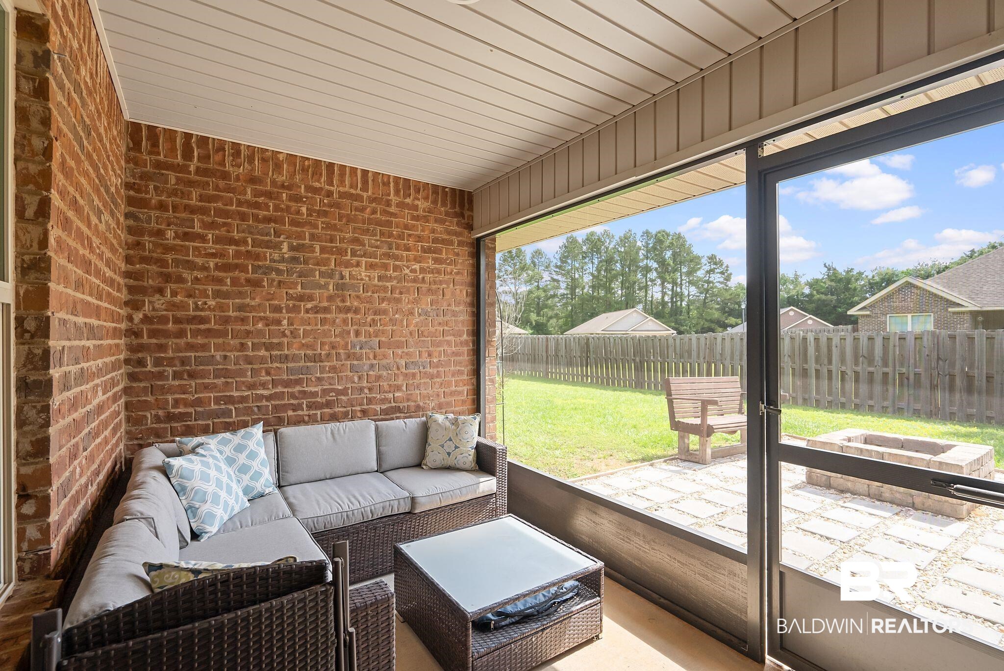 22076 Garland Loop Silverhill, AL 36576 - Photo 19 of 27 Screened-in porch featuring a brick exterior wall, a white slatted ceiling, and an exterior door leading to the backyard