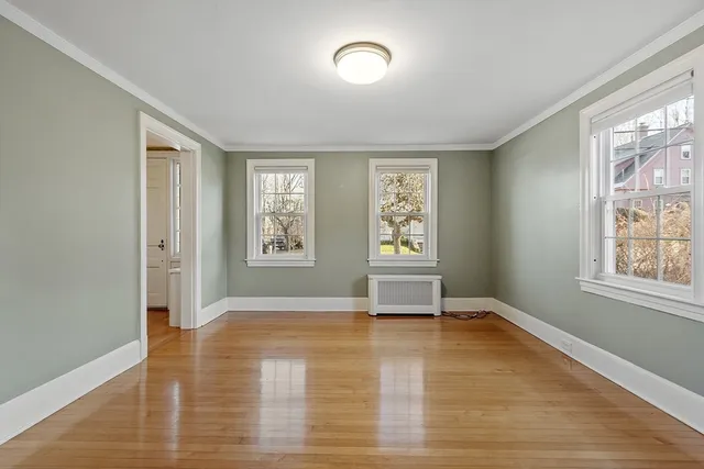 an empty room with wooden floor fireplace and windows
