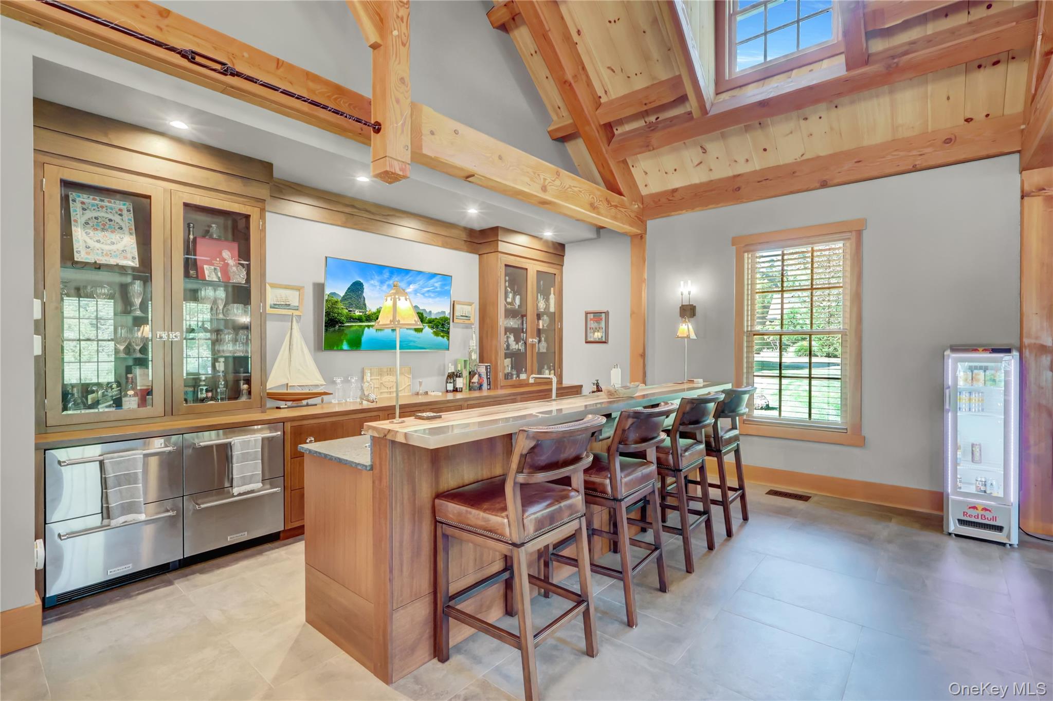63 Dyke Road Setauket, NY 11733 - Photo 19 of 49 Indoor wet bar featuring glass insert cabinets, brown cabinets, beamed ceiling, high vaulted ceiling, and light stone counters