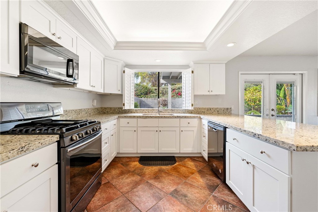 5855 Sunset Ranch Drive Riverside, CA 92506 - Photo 3 of 36 a kitchen with granite countertop white cabinets a window and stainless steel appliances