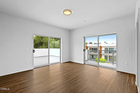 a view of an empty room with window and wooden floor