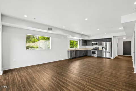 a view of an empty room with wooden floor and windows
