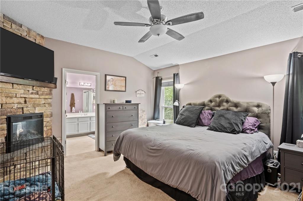 11204 Clayford Ridge Charlotte, NC 28215 - Photo 13 of 37 a bedroom with a bed a flat screen tv and a fireplace
