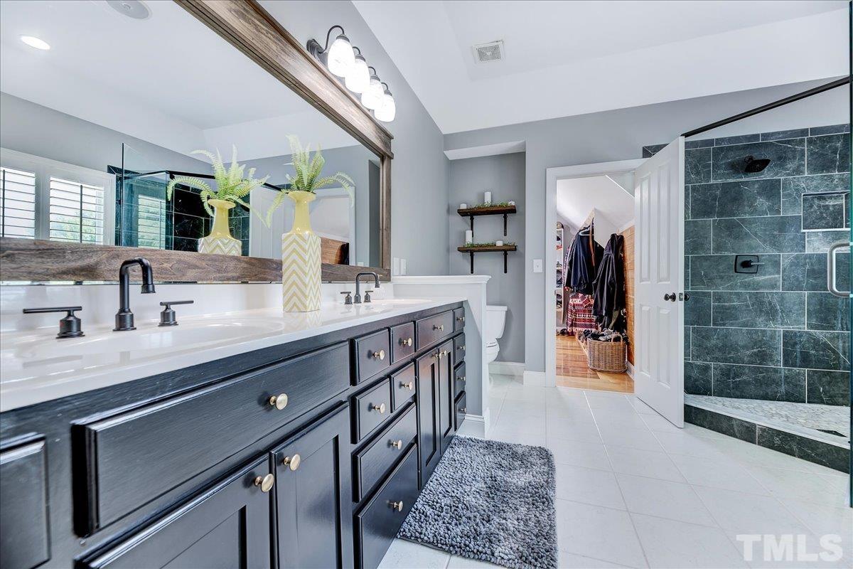 7033 Daniel Road Wake Forest, NC 27587 - Photo 44 of 63 a spacious bathroom with a double vanity sink a mirror and shower
