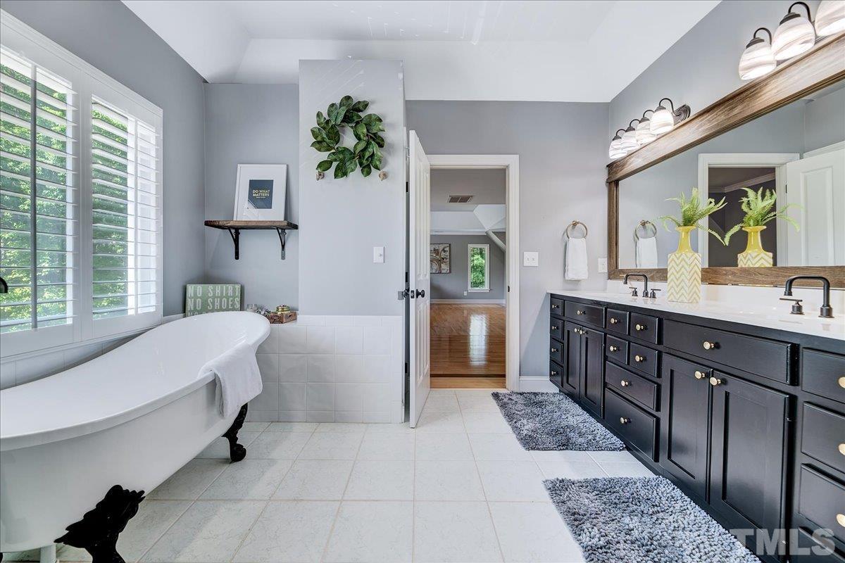 7033 Daniel Road Wake Forest, NC 27587 - Photo 46 of 63 a spacious en suite bathroom with a double vanity sink a tub and a mirror