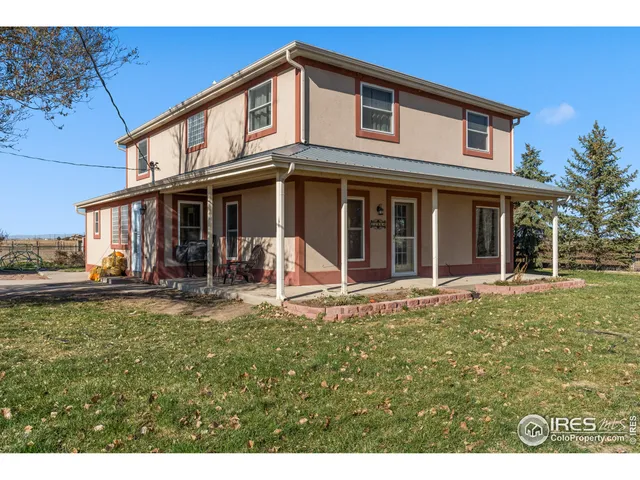 a view of a white house with large windows and a table and chairs in patio