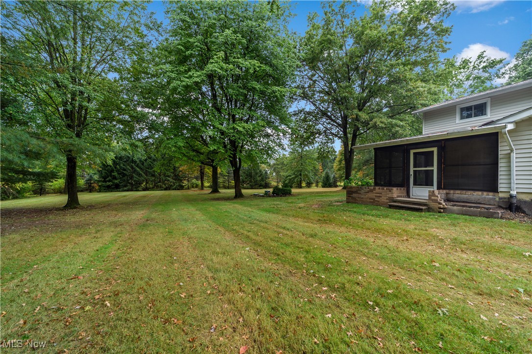 648 Rehwinkle Road Northfield, OH 44067 - Photo 26 of 38 View of green lawn with a sunroom, entry steps, and view of scattered trees