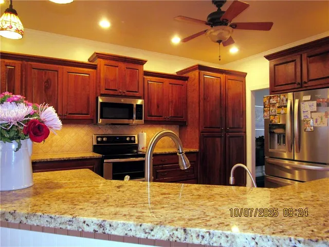 a kitchen with stainless steel appliances granite countertop a refrigerator a stove top oven a sink and dishwasher