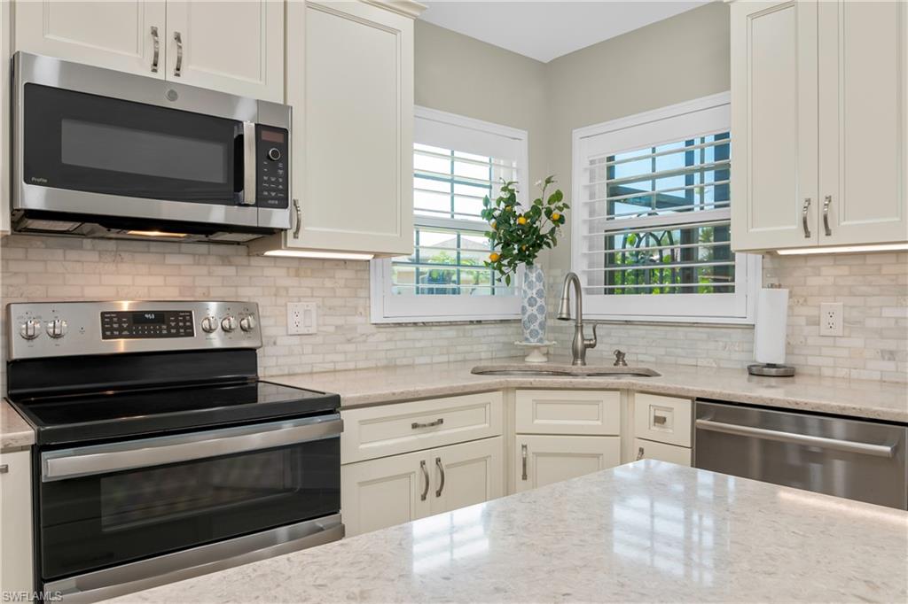 20771 Persimmon Place Estero, FL 33928 - Photo 11 of 50 a kitchen with stainless steel appliances a stove sink microwave and cabinets