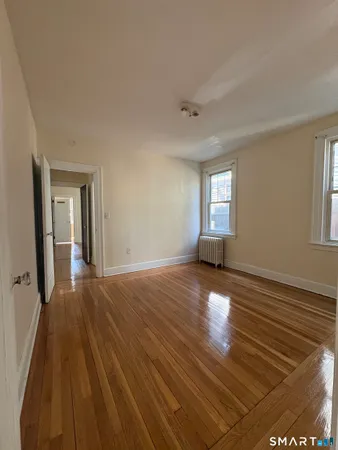 a view of empty room with window and wooden floor