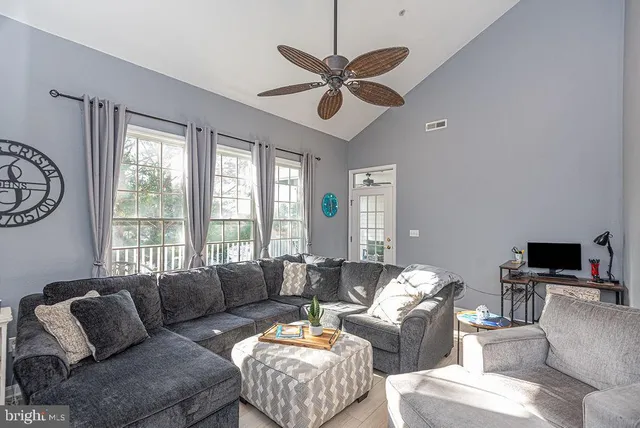 a living room with furniture a ceiling fan and a large window