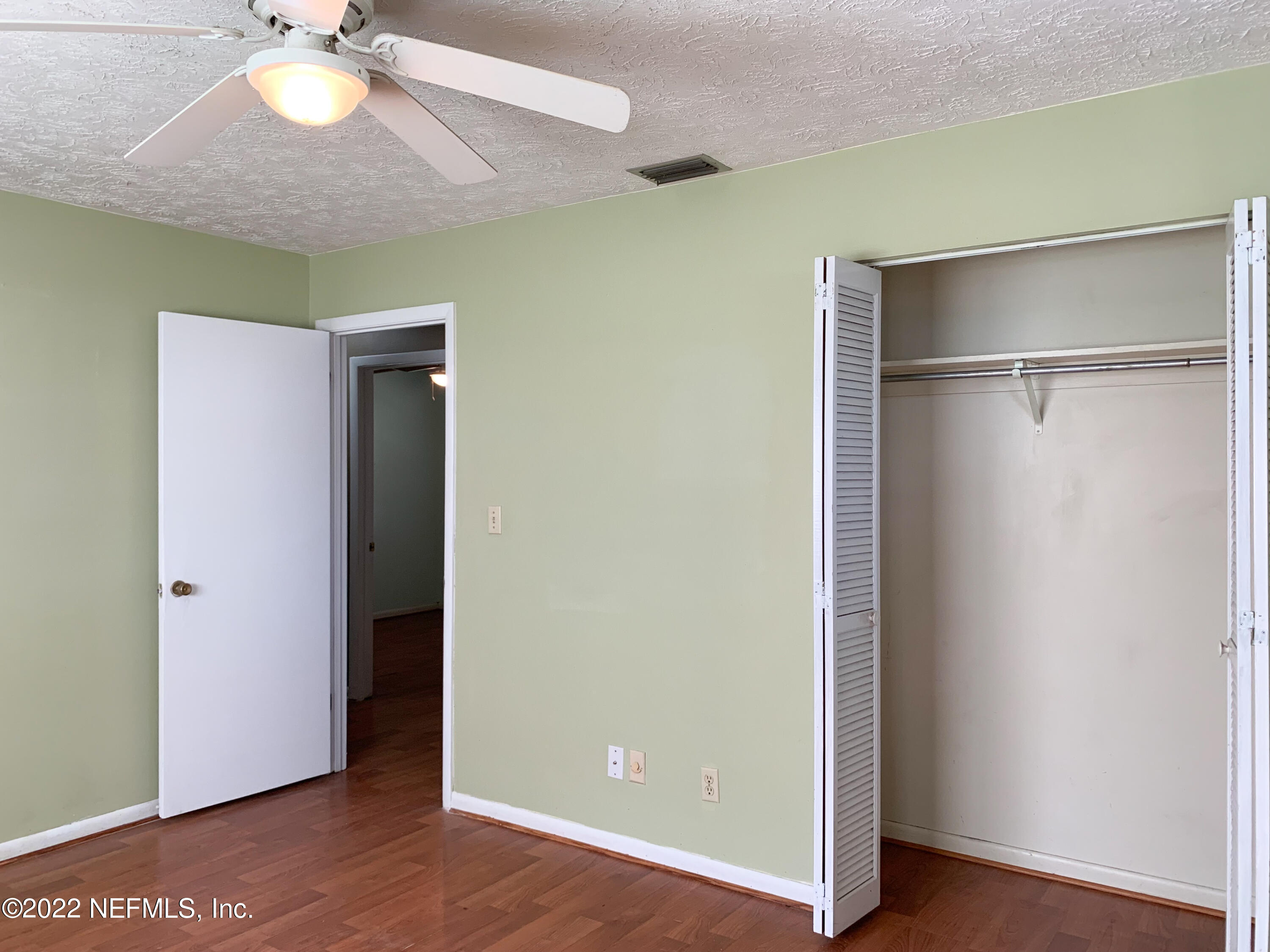 6771 Deer Springs Road Keystone Heights, FL 32656 - Photo 13 of 23 a view of an empty room with wooden floor and a ceiling fan