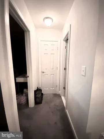 a view of a hallway with wooden floor and a bathroom