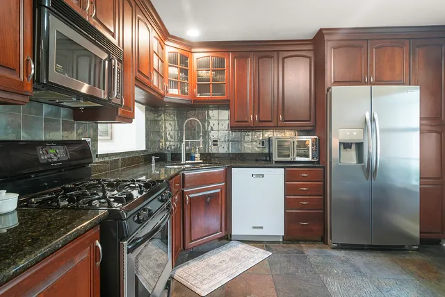 a kitchen with stainless steel appliances granite countertop a stove a refrigerator and a sink