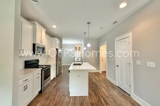 a large kitchen with cabinets wooden floor and stainless steel appliances