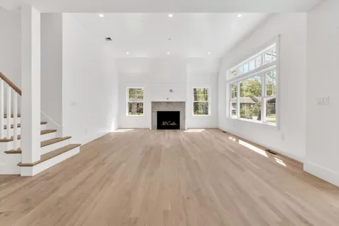 an empty room with windows fireplace and wooden floor