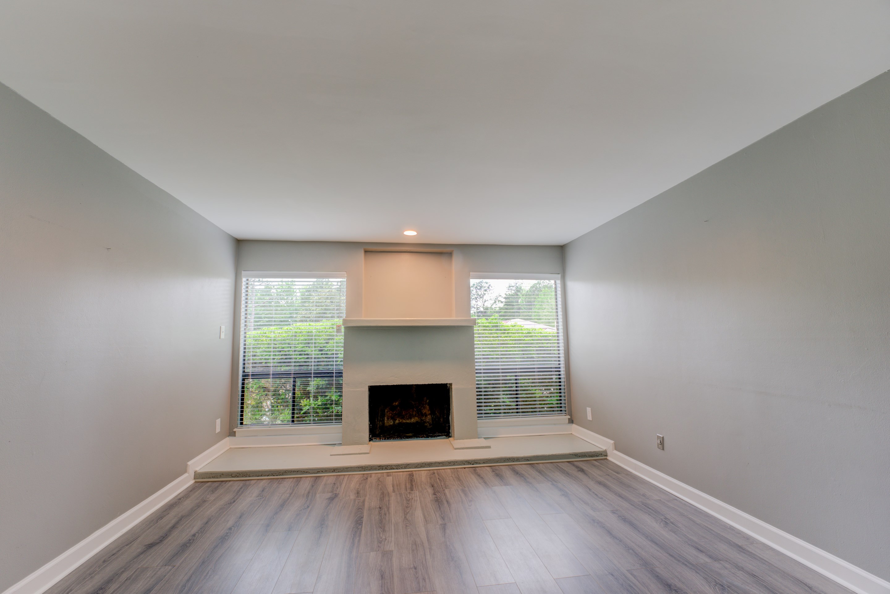an empty room with wooden floor a fireplace and windows