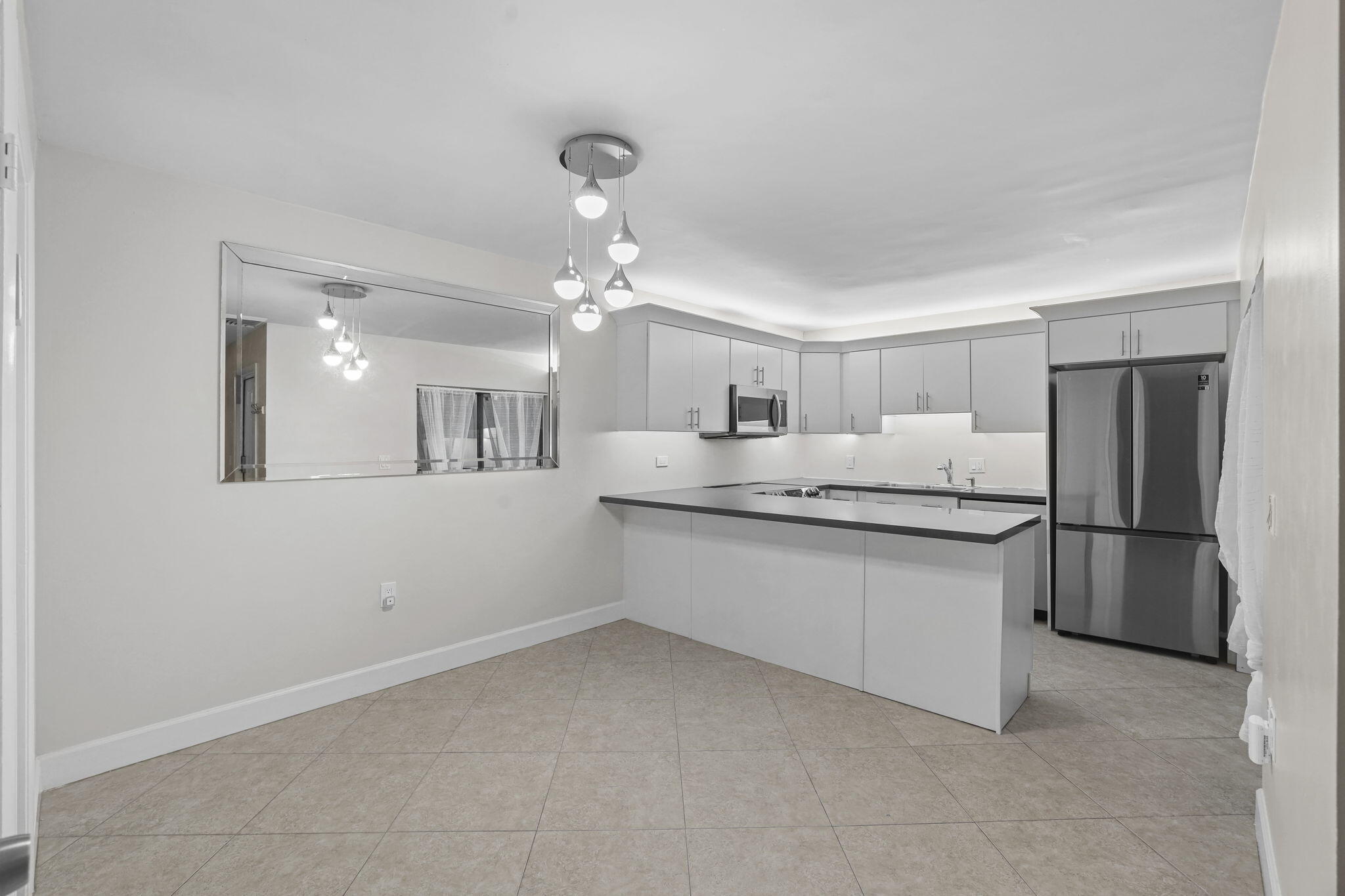 617 6th Lane Palm Beach Gardens, FL 33418 - Photo 17 of 49 a large white kitchen with a refrigerator a sink dishwasher with a dining table and chairs