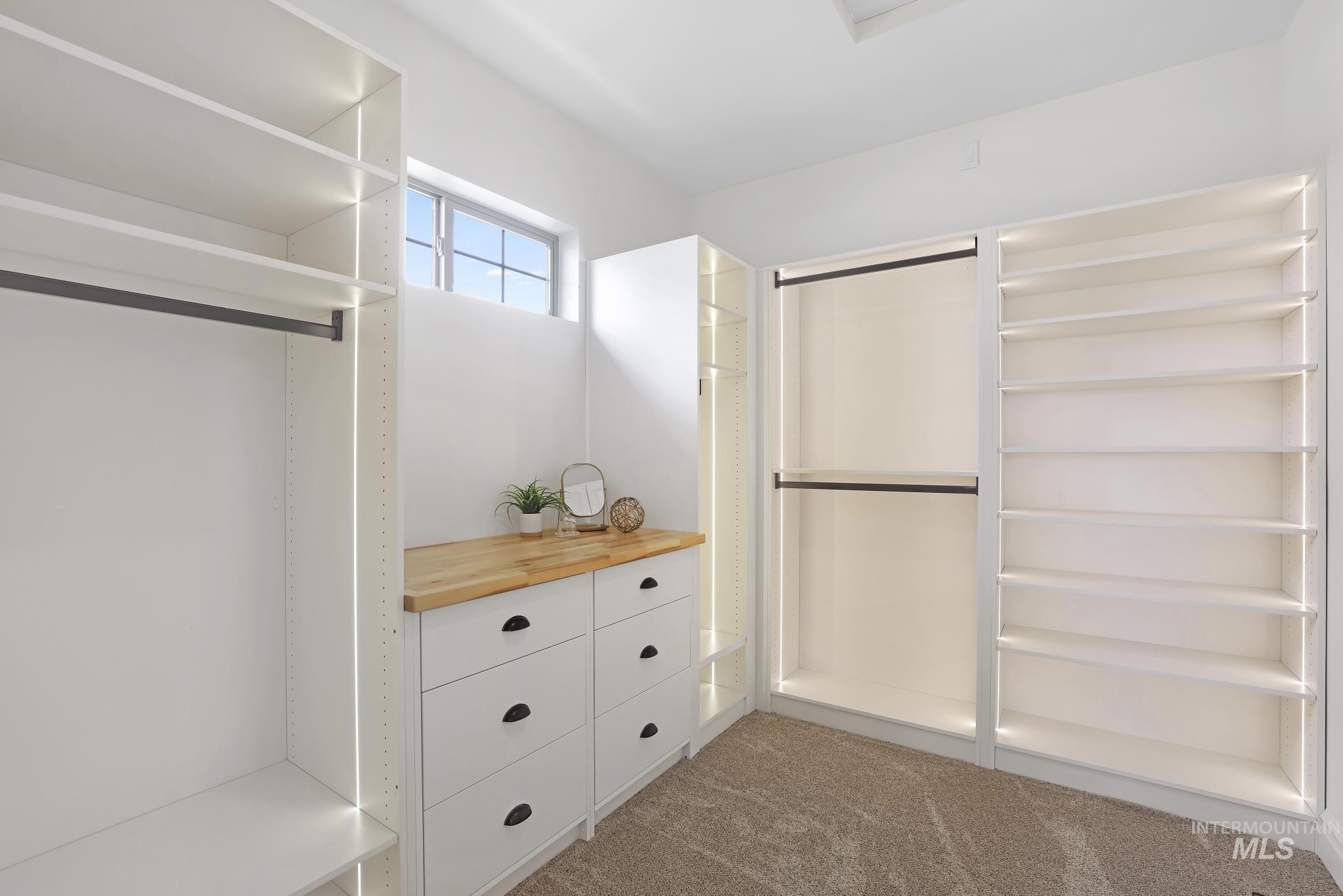 866 Quartz Road Kimberly, ID 83341 - Photo 25 of 48 Walk-in closet featuring built-in white cabinetry, multiple hanging rods, extensive shelving, light wood-finish countertop, and plush carpet flooring