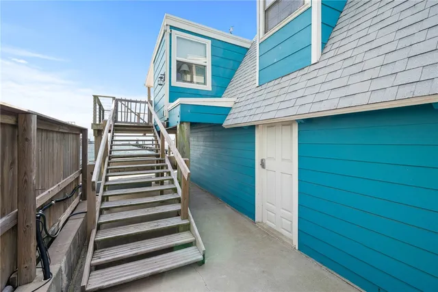 a view of a house with wooden deck stairs and furniture