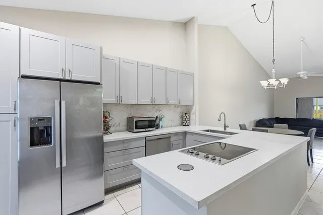 a kitchen that has a refrigerator a sink and white cabinets