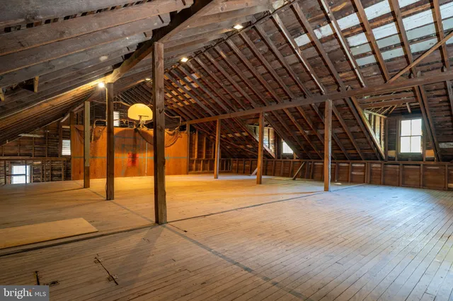 a view of an empty room with wooden floor and windows