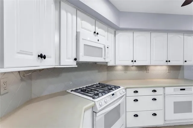 a kitchen with granite countertop white cabinets and white appliances