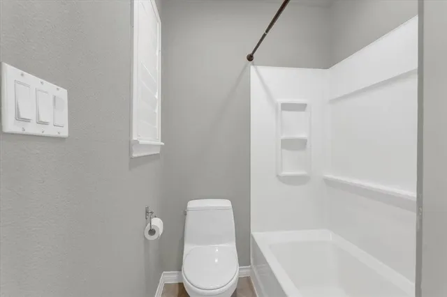 a white toilet sitting next to a bath tub