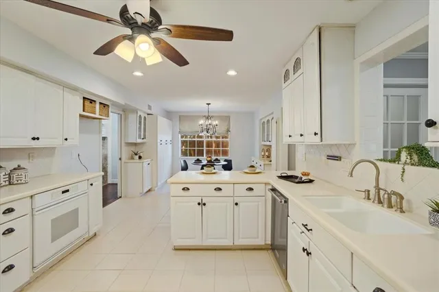 a large white kitchen with a sink a stove a chimney cabinets and furniture