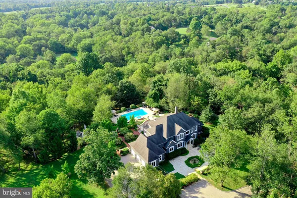 an aerial view of a house with a lush green forest