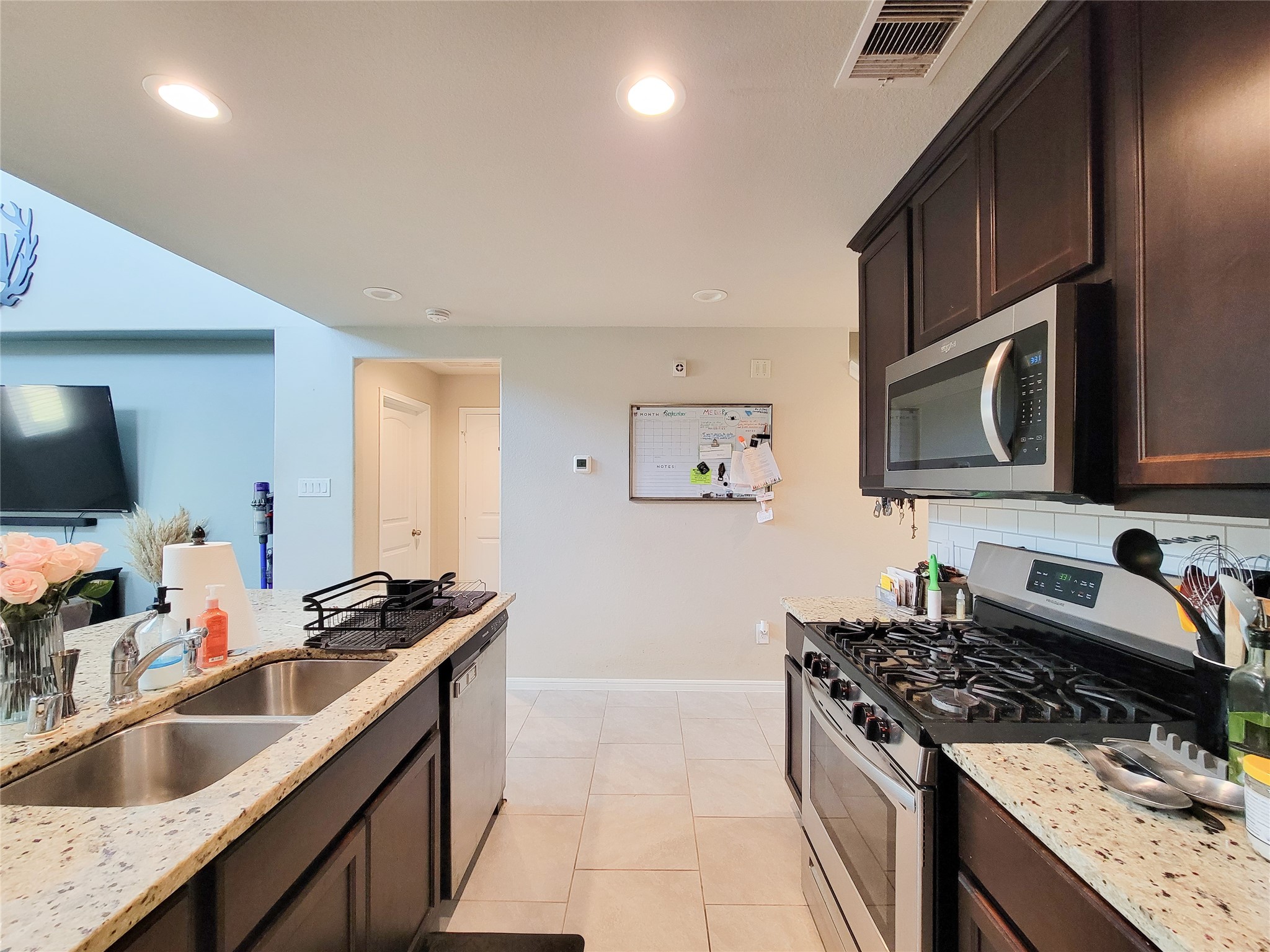 8003 Ecru Lane Rosharon, TX 77583 - Photo 7 of 35 a kitchen with stainless steel appliances granite countertop a sink stove and microwave