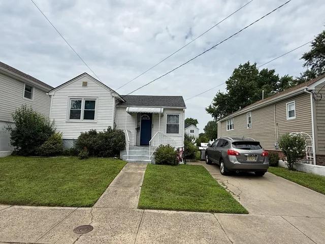 a front view of a house with a garden and trees