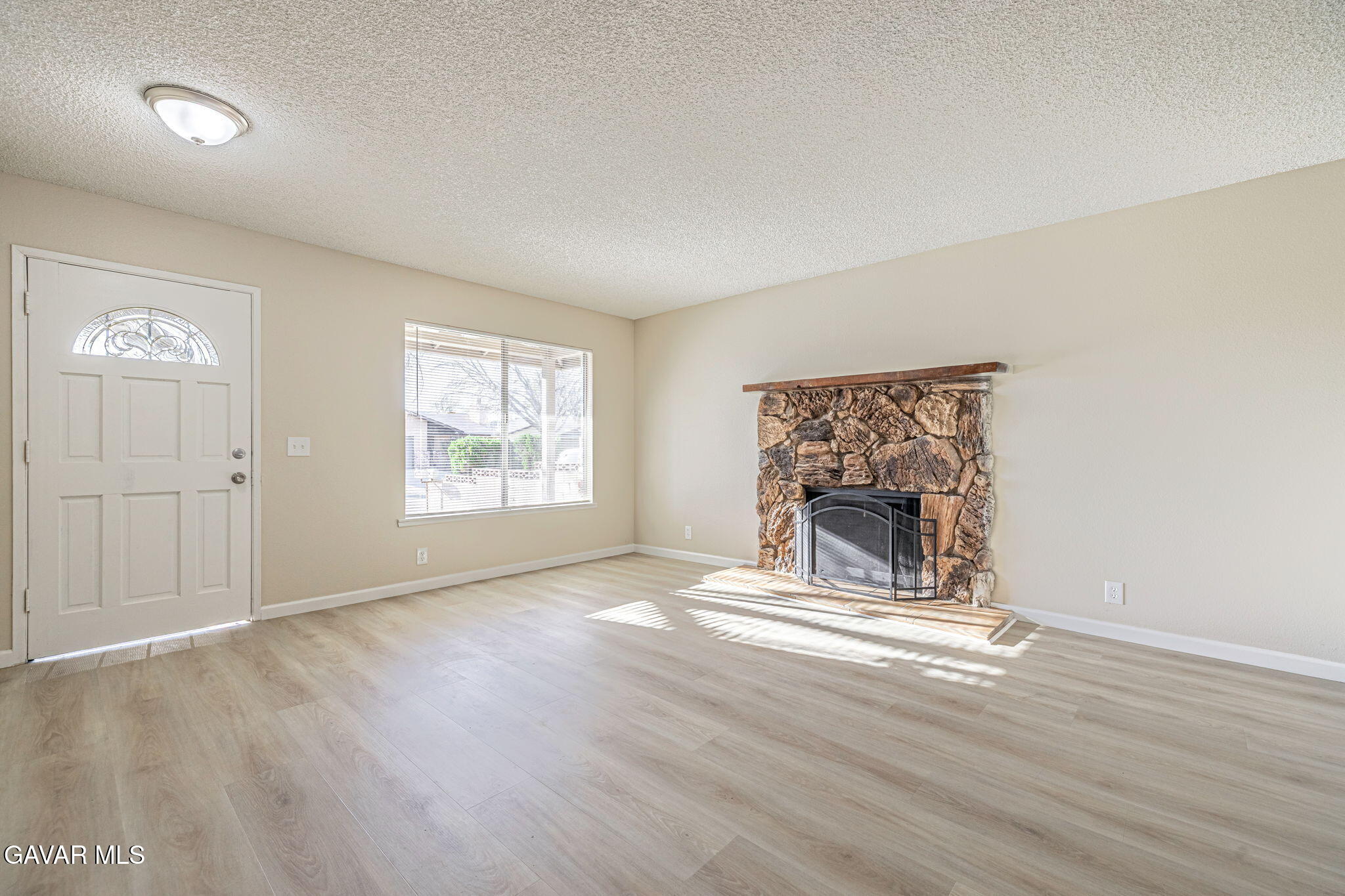 44422 Sancroft Avenue Lancaster, CA 93535 - Photo 9 of 35 an empty room with wooden floor fireplace and windows