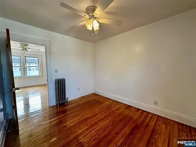 a view of empty room with wooden floor and fan