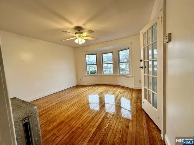 a view of an empty room with window and wooden floor
