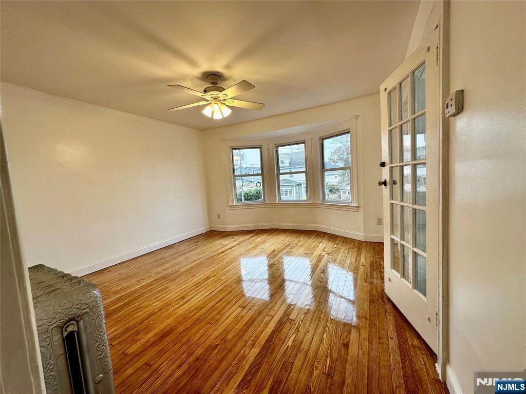 227 Hamilton Avenue, Unit 2 Hasbrouck Heights, NJ 07604 - Photo 6 of 27 a view of an empty room with window and wooden floor