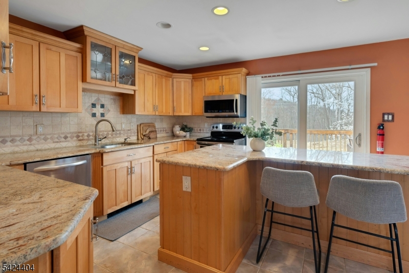 4 Andover Mohawk Road Sparta, NJ 07871 - Photo 7 of 35 a kitchen with stainless steel appliances granite countertop a stove a sink dishwasher a microwave oven and a dining table with wooden cabinet