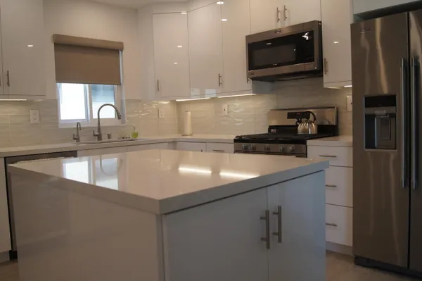 a kitchen with a sink dishwasher and white cabinets with wooden floor