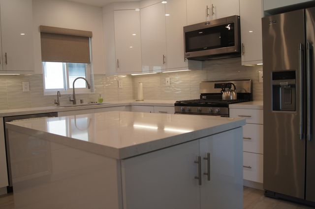 a kitchen with a sink dishwasher and white cabinets with wooden floor