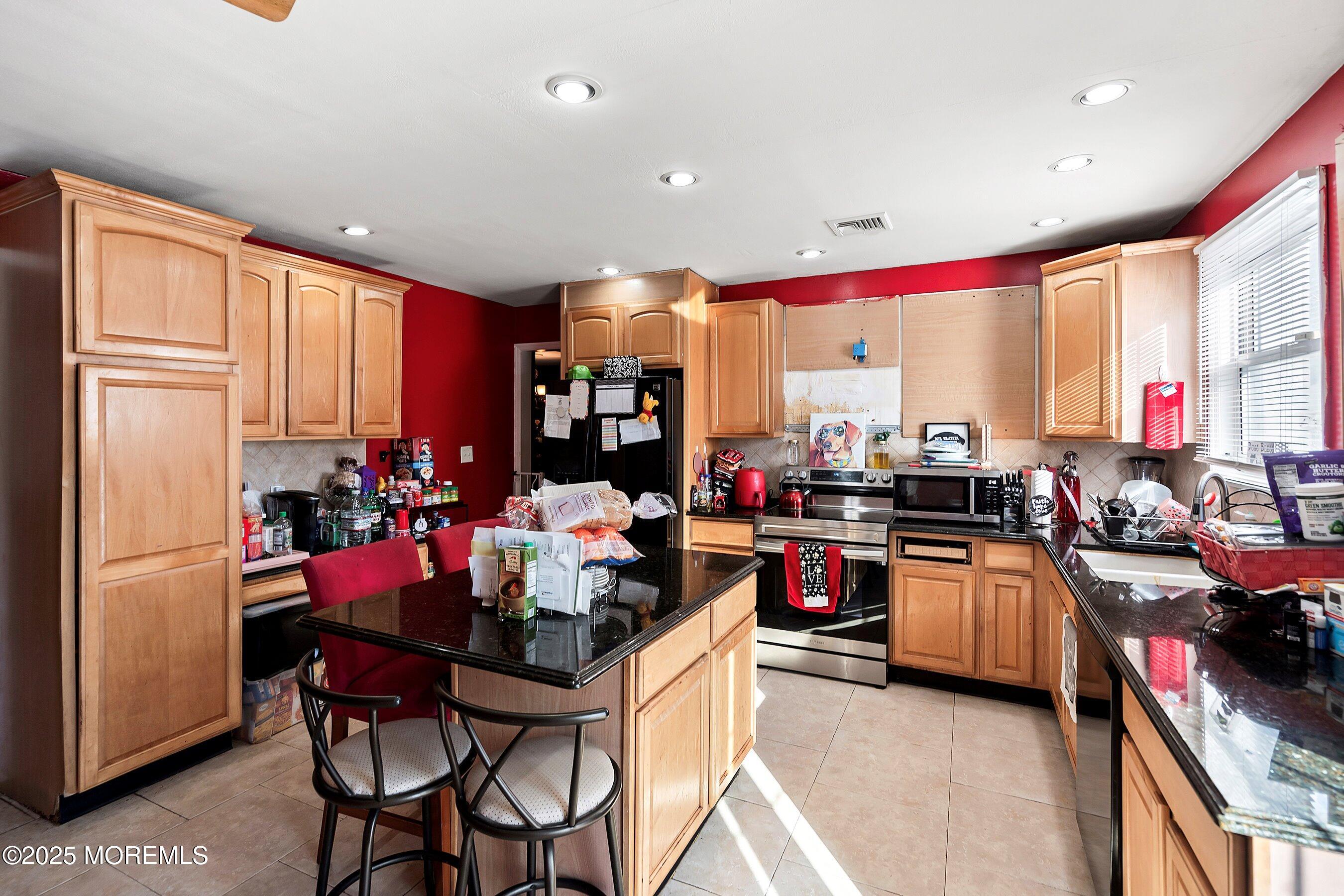 319 Jackson Mills Road Freehold, NJ 07728 - Photo 10 of 30 a kitchen with stainless steel appliances granite countertop a stove top oven a sink dishwasher and chairs with wooden floor