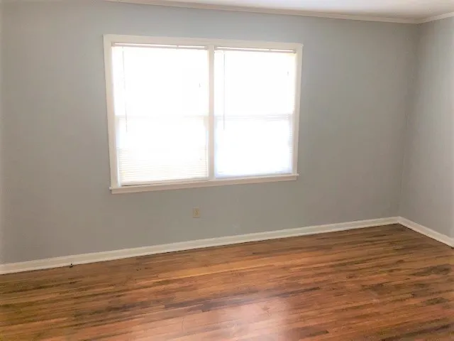 an empty room with wooden floor and a window
