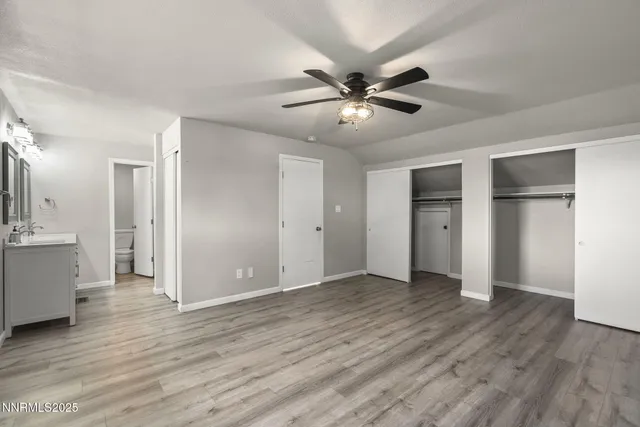 a view of an empty room with wooden floor and a ceiling fan